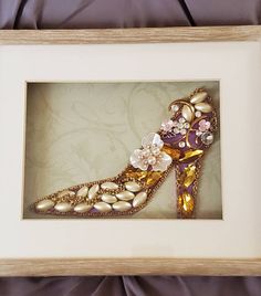 an ornate shoe with flowers is framed in a white wooden frame on a purple fabric