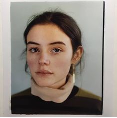 a woman with brown hair wearing a turtle neck sweater and earrings looking at the camera