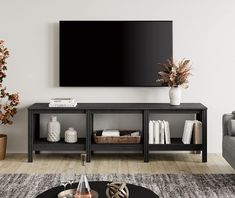 a flat screen tv mounted to the side of a wall above a black coffee table