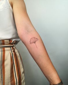 a woman's arm with a single flower tattoo on the left side of her arm