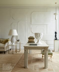 a living room filled with furniture and a white table topped with a vase next to a lamp