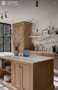 an open kitchen with wooden cabinets and white marble counter tops, along with a laptop on the island