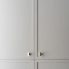 two white cupboards with brass handles and knobs on the doors, one is closed