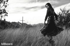 a woman in a dress is walking through tall grass