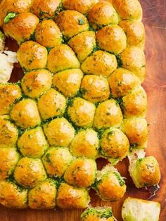 a wooden cutting board topped with lots of bread balls and broccoli florets