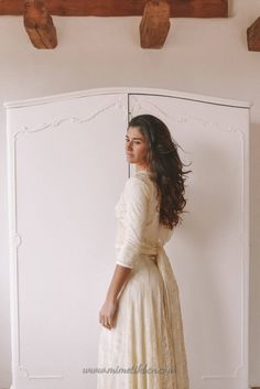 a woman standing in front of a mirror wearing a white dress and holding her hand on her hip