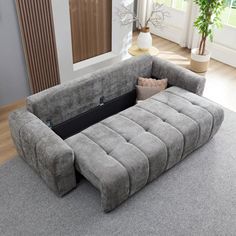 a large gray couch sitting on top of a carpeted floor next to a window