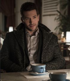 a man sitting at a table with a cup and saucer