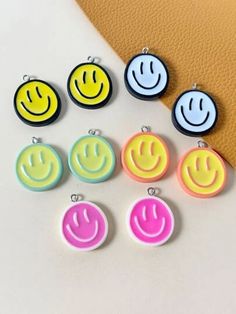 six different colored smiley face earrings sitting on top of a table