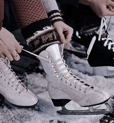 two people are tying their ice skates in the snow while another person is holding on to them