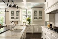 a large kitchen with white cabinets and marble counter tops