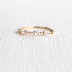 a yellow gold ring with three diamonds on the side, sitting on a white surface