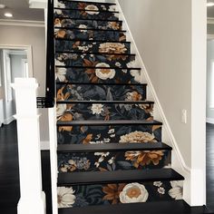 the stairs are decorated with floral wallpaper and black painted stair treads that lead up to an upstairs landing