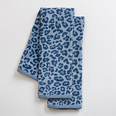 two blue and white leopard print napkins sitting on top of each other in front of a white wall