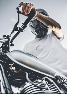 a man wearing a motorcycle helmet and holding onto the handlebars of his motorcycle