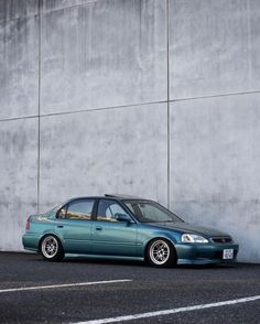 a blue car parked in front of a concrete wall