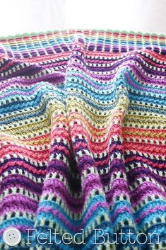 a multicolored crocheted blanket sitting on top of a table