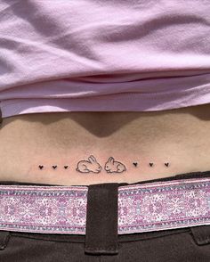 a woman's stomach with two rabbits and hearts tattoo on her lower back side