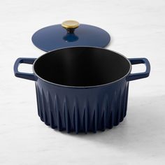 a blue pot with a lid sitting on top of a white counter next to a black pan