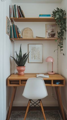 a wooden desk topped with a white chair next to a shelf filled with books and plants