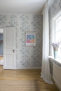 an empty room with blue and white wallpaper, wood flooring and a painting on the wall