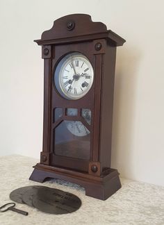 an old fashioned clock sitting on top of a table next to a pair of scissors