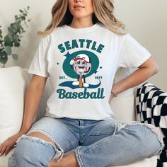 Show off your love for the Seattle Mariners with our retro style shirt! Crafted with premium materials, this shirt is both comfortable and durable, making it perfect for game days or everyday wear. Whether you're cheering from the stands or watching from home, this shirt is sure to make you stand out as a true fan. Support your favorite team in style with our vintage Seattle Mariners tshirt today! ⚾ T-shirt: - Comfort Colors - Made with medium pre-shrunk fabric (6.1 oz/yd² (206.8 g/m consisting Baseball Season Fan Apparel Tops With Sublimation Print, Graphic Print Shirt For Baseball Season Sports Events, Graphic Print Shirt For Baseball Season, Letter Print Shirt For Baseball Season, Retro Cotton T-shirt For Fan Gear, Baseball Season Fan Merchandise Graphic Tee Shirt, Baseball Season Fan Merchandise Graphic Tee, Baseball Season Fan Merchandise Graphic Print Tops, Graphic Tee Shirt For Baseball Season Fan Merchandise