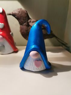 two little gnomes sitting on top of a counter next to each other, one red and one blue