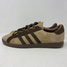 Elevate your shoe game with these Adidas Stapfen SPZL shoes in a stylish brown desert colorway. These sneakers feature ghillie-style lacing, dark brownish gum rubber outsole, and traction and stability patterned outsole for maximum comfort and style. The brown suede three-stripes and heel tab, along with the minimalist design, give these shoes a sleek and modern look that will elevate any outfit. Perfect for any season, these shoes are suitable for various activities such as gym and training, wa Brown Lace-up Sneakers With Vented Sides, Brown Sports Sneakers With Vented Sides, Retro Brown Sneakers For Sports, Brown Sneakers With Vented Sides For Streetwear, Brown Sneakers For Streetwear With Vented Sides, Classic Brown Adidas Sneakers, Brown Adidas Sneakers With Rubber Sole, Vintage Brown Sneakers With Cushioned Footbed, Classic Brown Sneakers For Outdoor