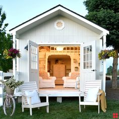 a white shed with two chairs and a bicycle parked in the front door area next to it