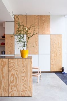 a yellow vase filled with green plants on top of a wooden counter in a kitchen