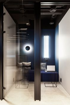 an office with black and white walls, blue couches, and glass partitions