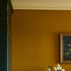 a vase with white flowers sitting on top of a table next to a framed painting