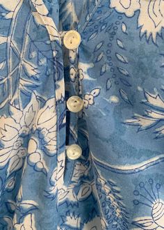 closeup of the buttons on a blue and white floral shirt