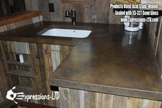 a kitchen counter top with a sink in the center and wood paneling on the walls