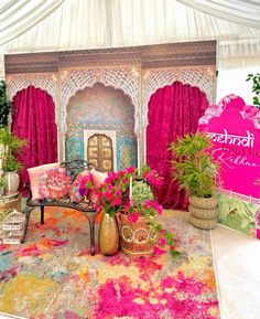 an elaborately decorated stage with pink curtains and flowers on the floor, surrounded by potted plants