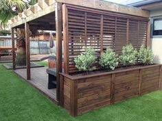 a wooden deck with planters on it next to a fenced in backyard area