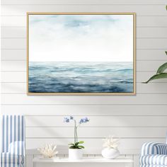 a living room with two chairs and a painting on the wall above it that says ocean waves