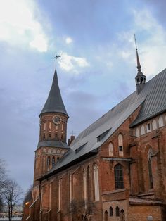 an old church with steeples and a clock on the tower is seen against a cloudy sky