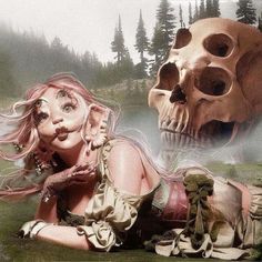 a woman laying on the ground next to a skull