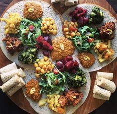 a platter filled with different types of food on top of a wooden table next to pita bread