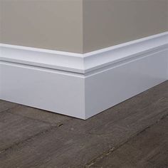 the corner of an empty room with wood flooring and white trim on the walls