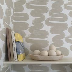 a shelf with two books and some balls on it next to a wallpapered bookcase