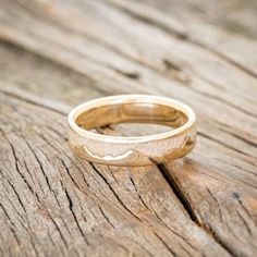 a gold wedding ring sitting on top of a wooden table