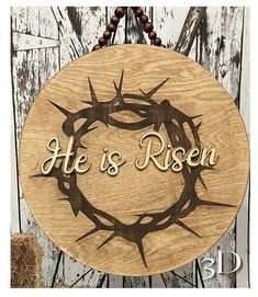 a wooden plaque with the words he is risen and crown of thorns on it