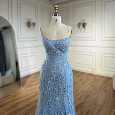 a dress on display in a room with white walls and wood flooring that has a mirror behind it