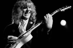 a black and white photo of a man playing an electric guitar