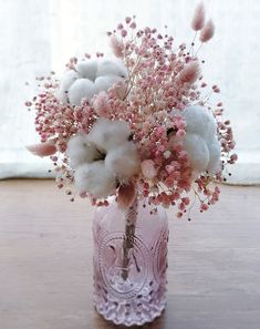 a pink vase filled with cotton and flowers