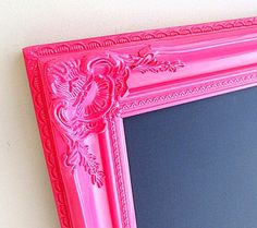 a pink framed mirror hanging on the wall