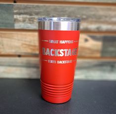 a red tumbler cup sitting on top of a table next to a wooden wall